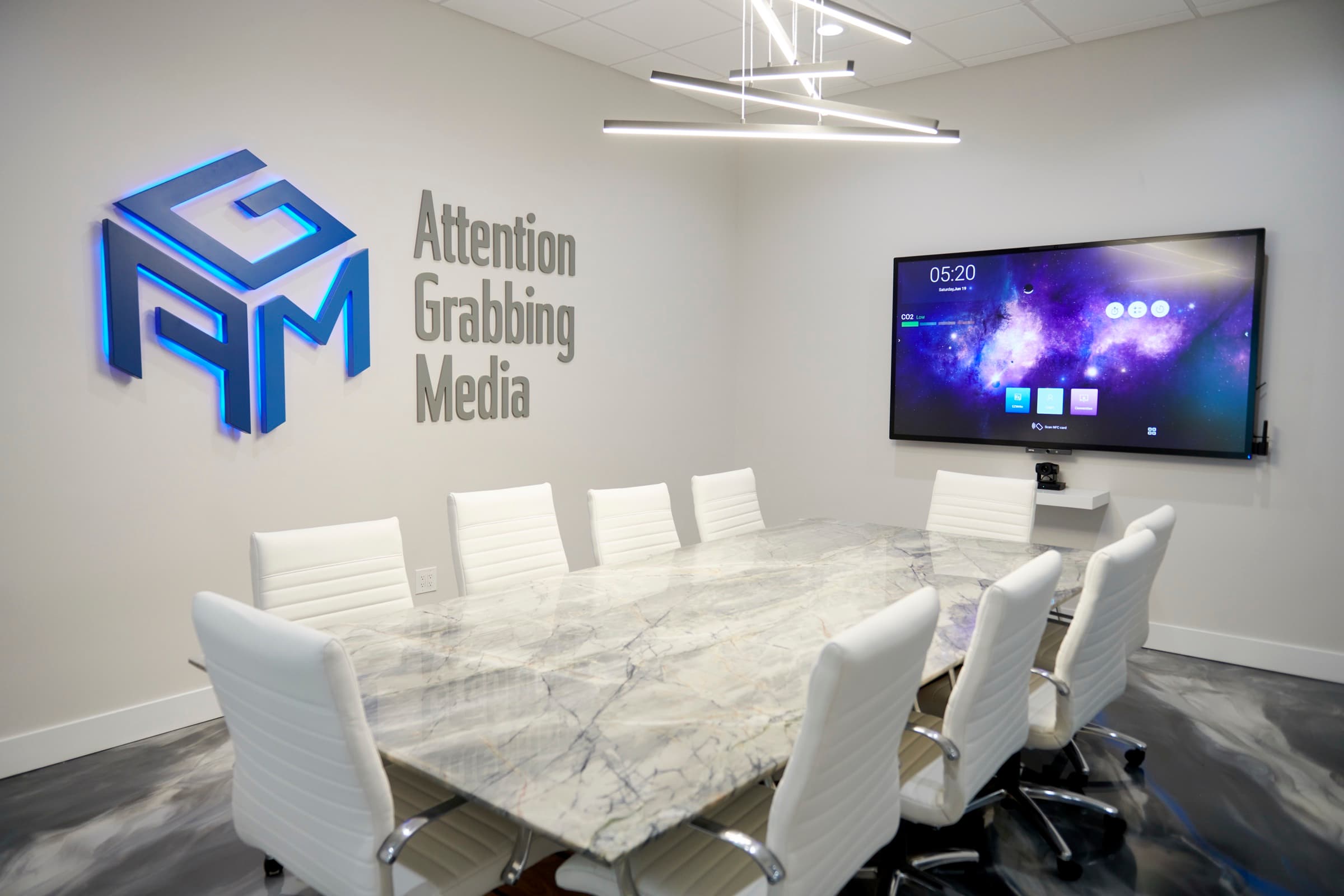 Conference room with a 3D AGM cube logo and Attention Grabbing Media lettering on the wall