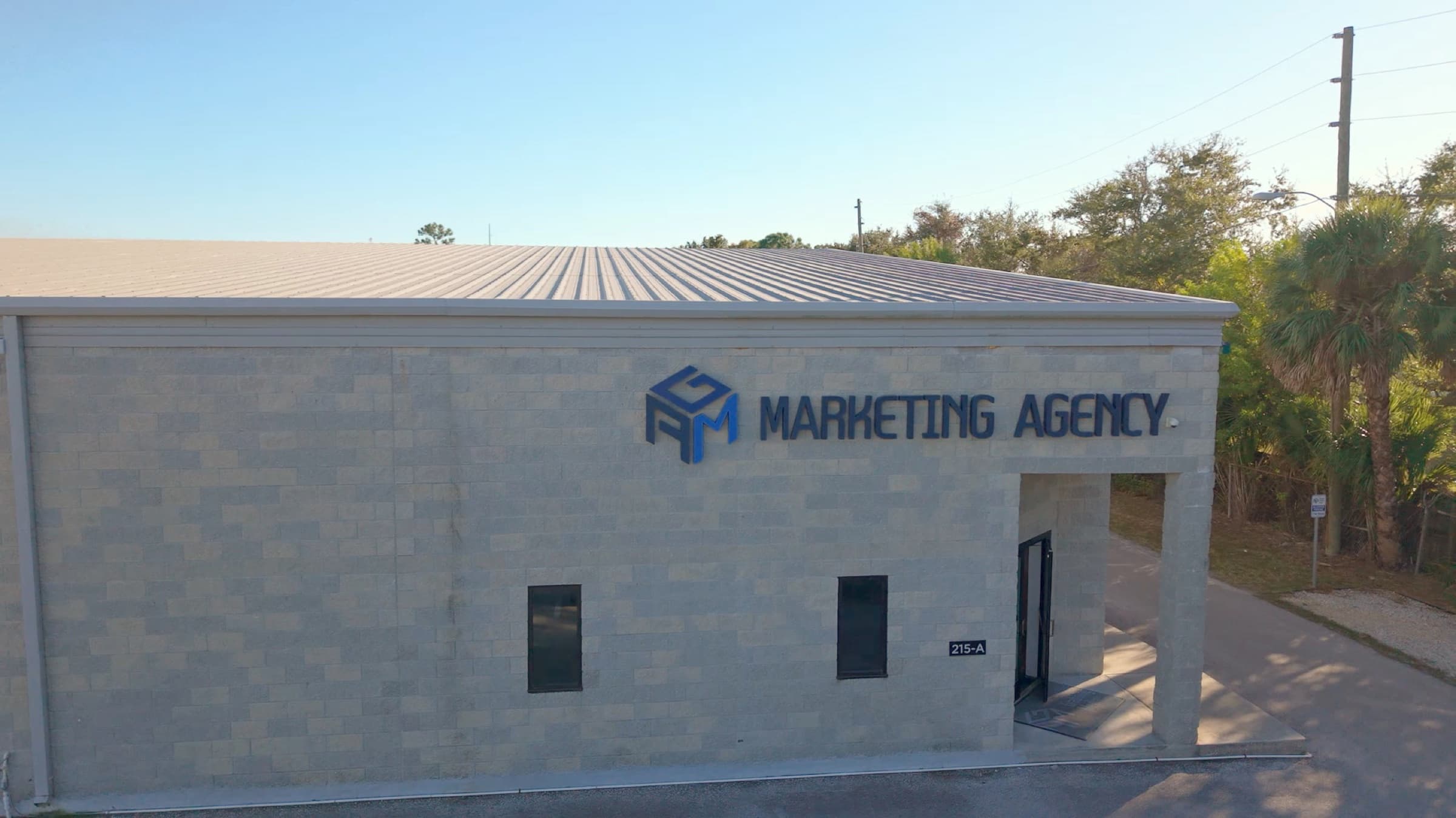Aerial view of the AGM Marketing Agency building with its rooftop sign, palm trees behind